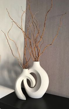 a white vase with branches in it sitting on a shelf