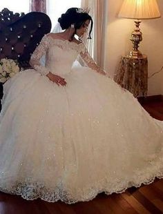 a woman in a white wedding dress sitting on a chair with her hand on her hip