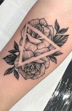 a black and white rose tattoo on the left arm with a triangle in it's center