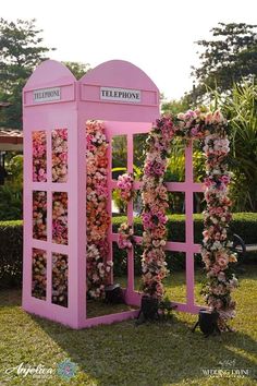 a pink phone booth decorated with flowers and greenery for an outdoor wedding or ceremony