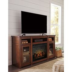 a flat screen tv sitting on top of a wooden entertainment center next to a fire place