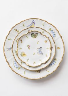 three white and gold plates with butterflies on them