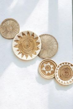 three woven baskets sitting on top of a white surface next to each other with sun designs