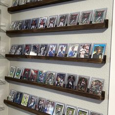 several wooden shelves filled with baseball cards on top of a white wall next to a mirror