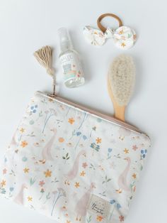 the contents of a cosmetic bag are laid out in front of it, including a brush and comb