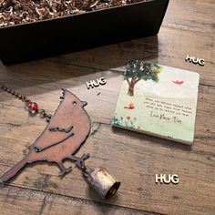 a wooden table topped with a metal bird necklace and a book on top of it