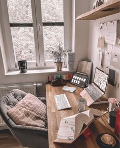 a desk with two laptops, books and papers on it in front of a window