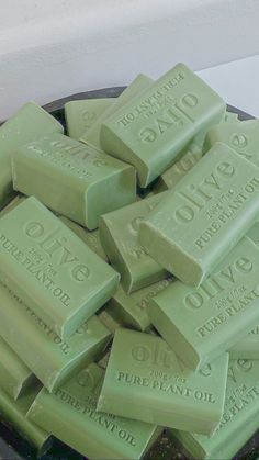 a pile of green soap bars sitting on top of a black tray next to a white wall