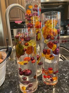 three glass vases filled with different types of candies on a counter top next to a sink