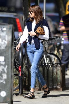 a woman walking down the street with her handbag in her pocket and shoes on