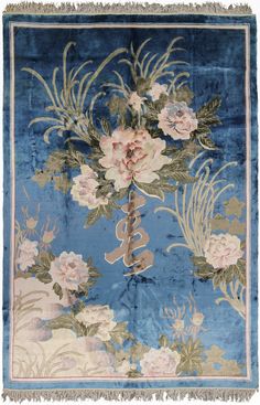 a blue rug with flowers on it and fringes hanging from the top of it