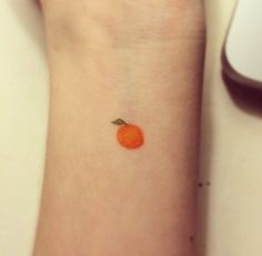 a small orange tattoo on the wrist