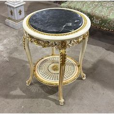 a marble topped end table with gold trimmings on the top and bottom, sitting in front of a couch