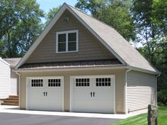 two garages with windows on each side of the doors are in front of a house