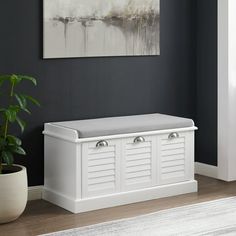 a white bench sitting next to a plant in a room with black walls and flooring