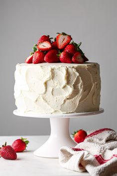 a cake with white frosting and strawberries on top, sitting on a table