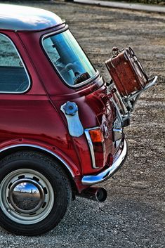 an old red car is parked on the side of the road with its door open