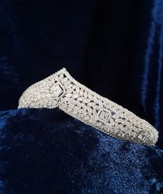 a diamond bracelet on a blue velvet surface, with the clasp partially closed to show it's intricate design