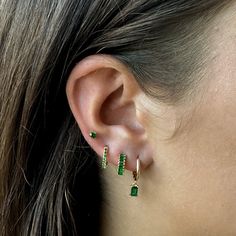 a close up of a person wearing some kind of earring with green stones on it