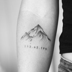 a black and white photo of a mountain tattoo on the left inner arm with date