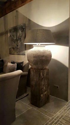 a lamp that is sitting on top of a wooden stump in front of a couch