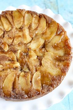 an apple pie sitting on top of a white paper plate next to a blue table cloth