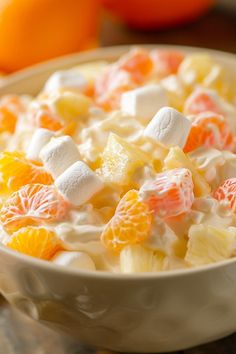 a bowl filled with fruit and marshmallows on top of a table