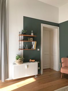 a living room with green walls and white radiator next to a chair in the corner