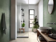 a bathroom with green tiles and a white sink sitting next to a walk in shower