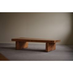 a wooden bench sitting on top of a cement floor next to a wall and window