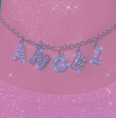 a necklace with the word angel on it is shown in front of a pink background