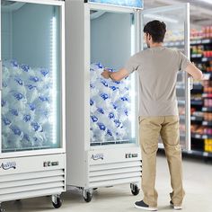 a man standing in front of two coolers filled with water and soda bottles at a grocery store