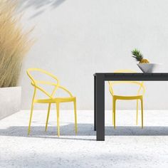 two yellow chairs and a black table in front of a white wall