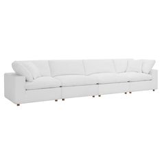 a large white couch sitting on top of a white floor next to a wooden table