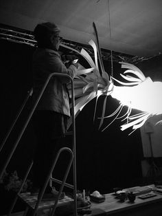 a woman is standing on a ladder and working on something that looks like an object