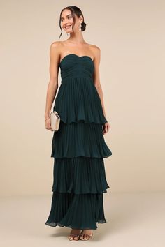 a woman in a strapless green dress with tiered layers and a handbag