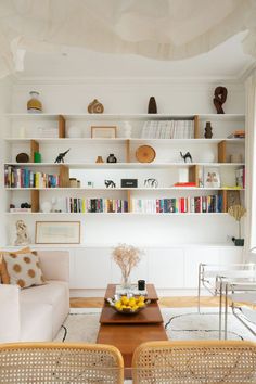 a living room filled with lots of furniture and bookshelves above the couches