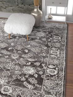 a large rug with an ornate design on the floor in front of a stone wall