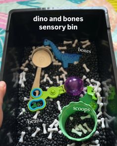 someone is holding a tray with different types of toys in it, including scissors and bones