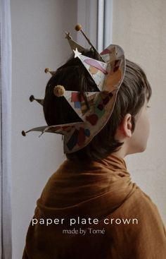 a young boy wearing a paper plate crown made by tome, with the words paper plate crown above his head