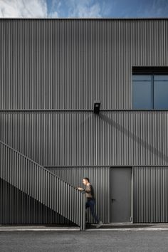 a man walking up the side of a building next to a metal stair case with windows