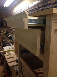 a wooden shelf with drawers and tools on it in a room filled with other woodworking supplies