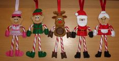 christmas ornaments are hanging on a table with candy canes and candies in the shape of santa's helpers