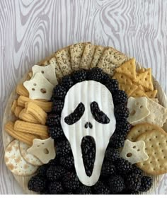 a plate with crackers and blackberries in the shape of a face