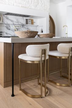 two white chairs sitting on top of a wooden floor in front of a countertop