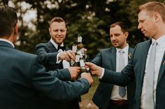 three men in suits are exchanging beer bottles