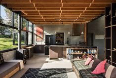 a living room filled with furniture and lots of windows next to a wooden ceiling covered in bookshelves