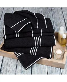 a tray with black towels and a candle on it next to a bottle of lotion