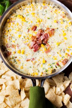 a pan filled with corn and bacon dip surrounded by tortilla chips