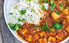 a white plate topped with rice and tofu next to some green garnish